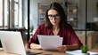© Arnab Dey - Focused latin hispanic business woman working on laptop computer reading financial document trader report in office. Thinking accountant entrepreneur manager businesswoman doing paperwork using pc