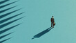© Pug - A solitary businessman stands confidently against a teal backdrop, casting a long shadow that symbolizes strength and determination in the corporate world.