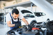 © Serhii - Mechanic working on car engine during service in garage