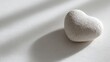 © KASUEMA SALAE - Minimalist background of a heart-shaped stone on a clean white medical surface, soft shadows, empathy and health care concept