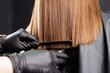 © Parilov - Haircut in salon, hairdresser uses comb and clippers to trim hairline of ends hair.