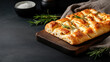 © syhin_stas - Italian focaccia bread, freshly baked with aromatic rosemary and herbs, resting on a dark wooden cutting board, creating a rustic and homemade culinary experience