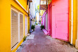 © Сергей Жмурчак - Narrow colorful alleyway with bright pink and yellow buildings on a sunny day in Willemstad Curacao