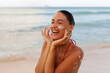 © Home-stock - Closeup of smiling young woman applying sunscreen on face at tropical beach