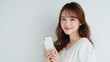 © Flower images - 日本人女性がスマートフォンを持って微笑んでいる姿。コミュニケーションやSNS利用シーンに適したイメージ素材。