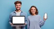 © Selvi - Happy young couple celebrating technology use with laptop and smartphone in bright blue background