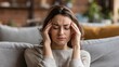 © Dao - Woman, sofa and stress with headache, migraine or anxiety with massaging temple in living room. Tension, mental health and wellness discomfort, crisis and worried female person frustrated in home