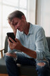 © Tj - Middle-aged man experiencing distress and anxiety while holding his phone, reacting to bad news, feeling stressed, frustrated, overwhelmed, and having tech fatigue or digital burnout