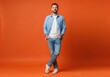 © Image stock - Man in casual outfit standing hands in pockets against orange background with full length