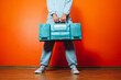 © VISTA by Westend61 - Man in blue tracksuit holding retro boombox against orange wall