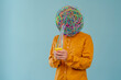 © VISTA by Westend61 - Man with mask of chaotic thoughts using smart phone against blue background