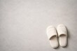 © AkuAku - Copy space layout showing a pair of comfortable slippers resting flat on a smooth pale grey textured background with text area