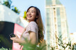 © StockPhotoRepublic - Young Asian woman smiling while holding a smartphone near a high-rise building