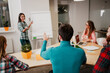© deagreez - Colleagues in a casual business meeting with a woman presenting at a flipchart and team members discussing ideas around a table