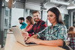 © deagreez - Young professionals collaborating in a modern coworking space using laptops and tablets, friendly startup team working together in an open office