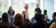 © Kate - Participant raising hand to ask a question in sunlit seminar with presenters softly out of focus, modern corporate setting