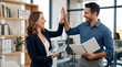 © Zulharyono - Two happy colleagues celebrating success with a high five in a modern office environment, looking pleased