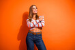 © deagreez - Young chic woman in striped top jeans pointing against orange backdrop for fashion lifestyle and shopping advertising