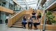© Svitlana - Business professionals relaxing on wide interior stairs in a contemporary office building, casual seated conversations, natural light from skylights above, informal yet creative workplace culture,