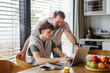 © Halfpoint - Father helping teenage son with diabetes with homework on laptop in kitchen.