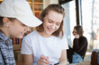 © RooM The Agency - Two smiling young women sitting in a cafe laughing and working together on a creative project