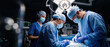 © Taras Roshchuk - Two surgeons and an assistant work together in an operating room. They wear masks and gloves while focusing on a surgical task. Medical equipment surrounds them