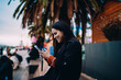© BullRun - Happy mixed race woman using smartphone application outdoors, cheerful hispanic girl browsing social media on mobile phone at evening park, authentic representation of connectivity and lifestyle.