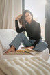 © gzorgz - Confident middle-aged woman reading a book and relaxing in her modern interior living-room