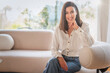 © gzorgz - Portrait of an elegant woman relaxing in an armchair in her bright, minimalist home