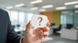 © erina - Business Professional Holding a Question Mark Symbol in Office Environment.