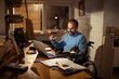 © Davor - Man in wheelchair working at home office with laptop and cat at night