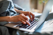 © Davor - Close-up of hands typing on laptop in bed at home