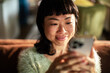 © Davor - Smiling woman using smartphone at home