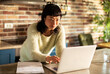 © Davor - Woman working on laptop at home kitchen counter
