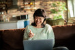 © Davor - Smiling woman video chatting on laptop at home