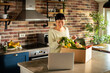© Davor - Smiling woman unboxing vegetable delivery box in home kitchen