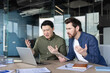 © Liubomir - Two diverse businessmen feeling angry and confused while collaborating and facing a severe technical error or problem, on a laptop with documents on the modern office desk