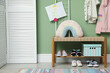 © New Africa - Shoe storage. Shelving unit with different kid's footwear near green wall indoors, space for text