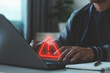 © THAWEERAT - Cyber security warning concept. Businessman typing on laptop, showing alert symbol and data risk notification. Cybersecurity, system error, data protection, hacking prevention, IT security services.