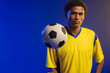 © Wavebreak Media - African American male balancing soccer ball at chest, posing in studio lighting with yellow jersey