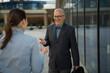 © Jelena - Senior businessman smiling discussing with female colleague outdoors
