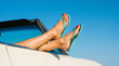 © ViskBx - Womans legs with turquoise flip flops resting on a car window against a clear blue sky, summer vacation and travel concept