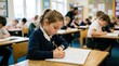 © Mey - A young girl concentrates intently on her math worksheet in a classroom setting. Several other elementary school students are also working at their desks, engaged in similar tasks.