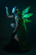 © faestock - portrait of female model wearing fantasy fairy costume, green dress, cloak, butterfly wings and crown. full length crouching  pose, isolated on dark studio background.