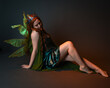 © faestock - portrait of female model wearing fantasy fairy costume, green dress, cloak, butterfly wings and crown. full length sitting pose, kneeling on floor, dark studio background.