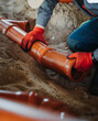 © eddgars - Close-up of worker joining PVC sewer pipes in sand trench. Underground drainage installation with focus on pipe connection and alignment.