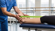 © Alex & M Studio - professional physical therapist in blue scrubs assisting patient with foot and ankle rehabilitation using green resistance band on medical table for sports injury recovery concept