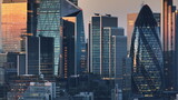 United Kingdom, London: Aerial view of London skyline at sunset, modern glass skyscrapers and the distinctive shape of 30 St Mary Axe, commonly known as The Gherkin, amidst the bustling cityscape