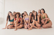 © deagreez - Diverse group of women in colorful underwear sitting together, showcasing body positivity, unity and natural beauty in a minimal studio setting
