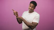© Krakenimages.com - Man pointing with fingers and smiling, bare hands visible wearing a pale t shirt in studio with pink backdrop; playful confidence.